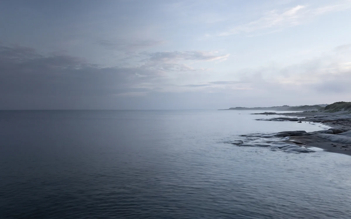 Calm open water along a rocky shore at dawn
