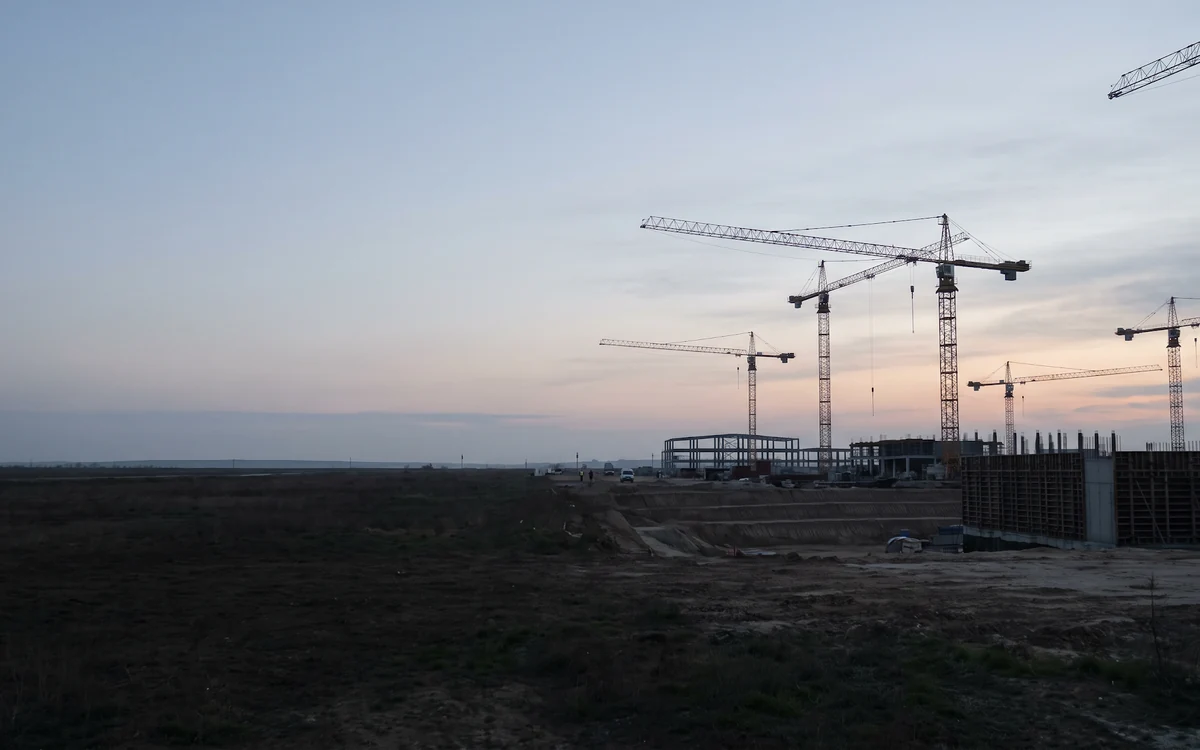 Tower cranes over a large construction site at dawn