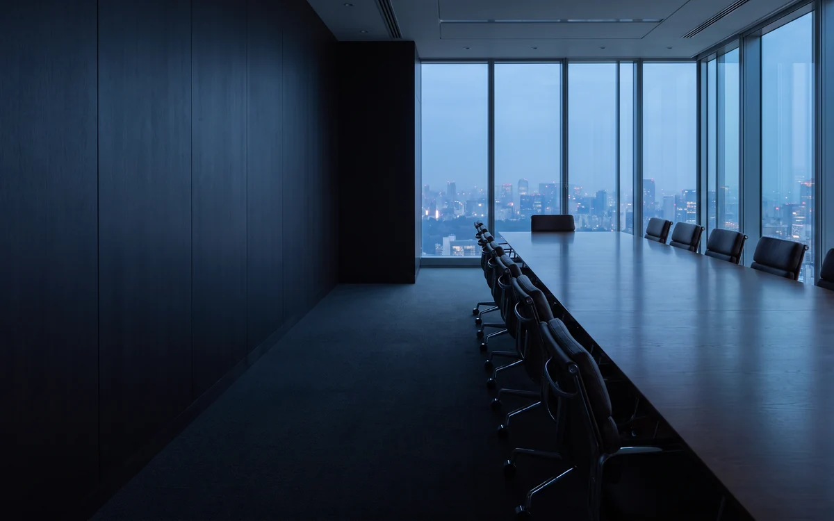 A boardroom at dusk with a city skyline beyond